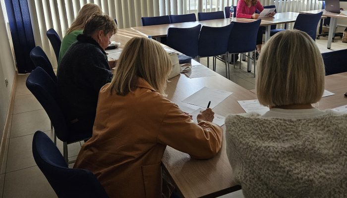 Uczestnicy szkolenia siedzą przy stole i robią notatki